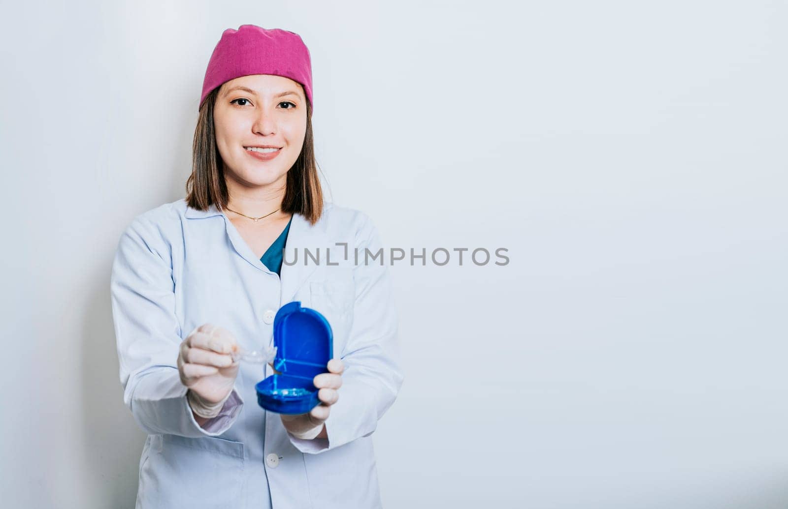 A dentist with retainers on isolated background, Portrait of smiling dentist with dental retainers isolated. Smiling young dentist showing some retainers