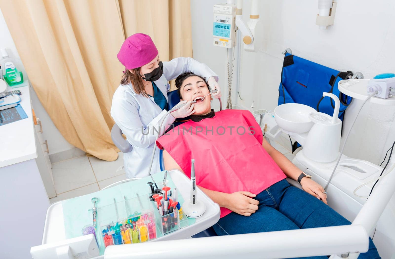 Stomatologist woman cleaning a patient's teeth, High angle of stomatologist cleaning woman's teeth, Dentist woman cleaning a patient's mouth with a drill. Stomatologist cleaning caries with drill
