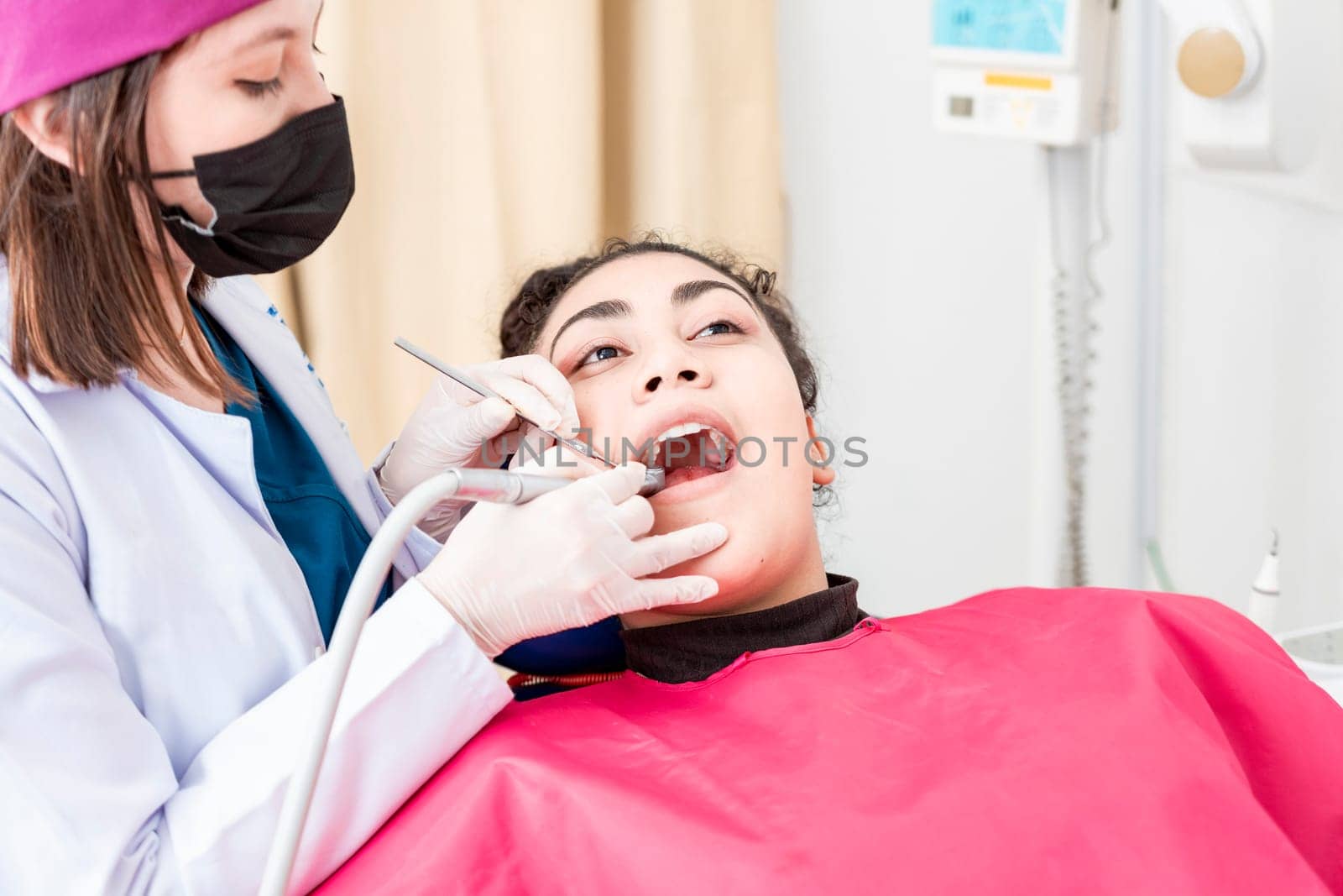 View of a dentist cleaning a patient mouth with a drill. Stomatologist cleaning a patient's teeth, Close-up of a stomatologist cleaning a woman's teeth, Stomatologist cleaning caries with drill