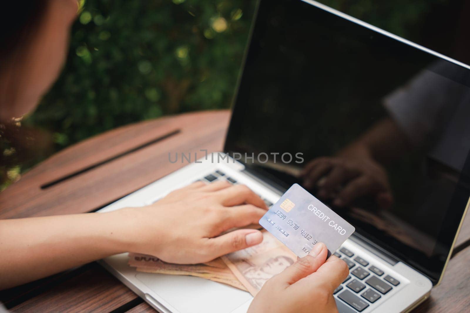Hands of businesswoman holding thai money and credit card on laptop computer, woman using working and shopping, Online e-commerce, internet banking
