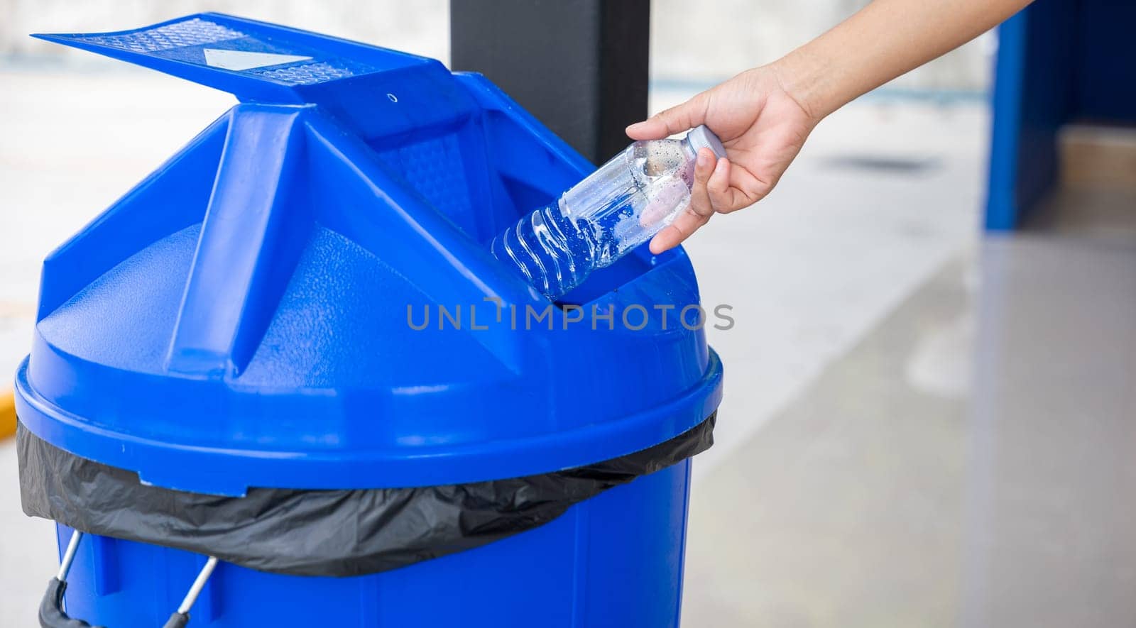 Close up woman hand throwing empty plastic water bottle into recycling bin, female throwing empty bottle to trash, Recycle rubbish, save the world and environment care