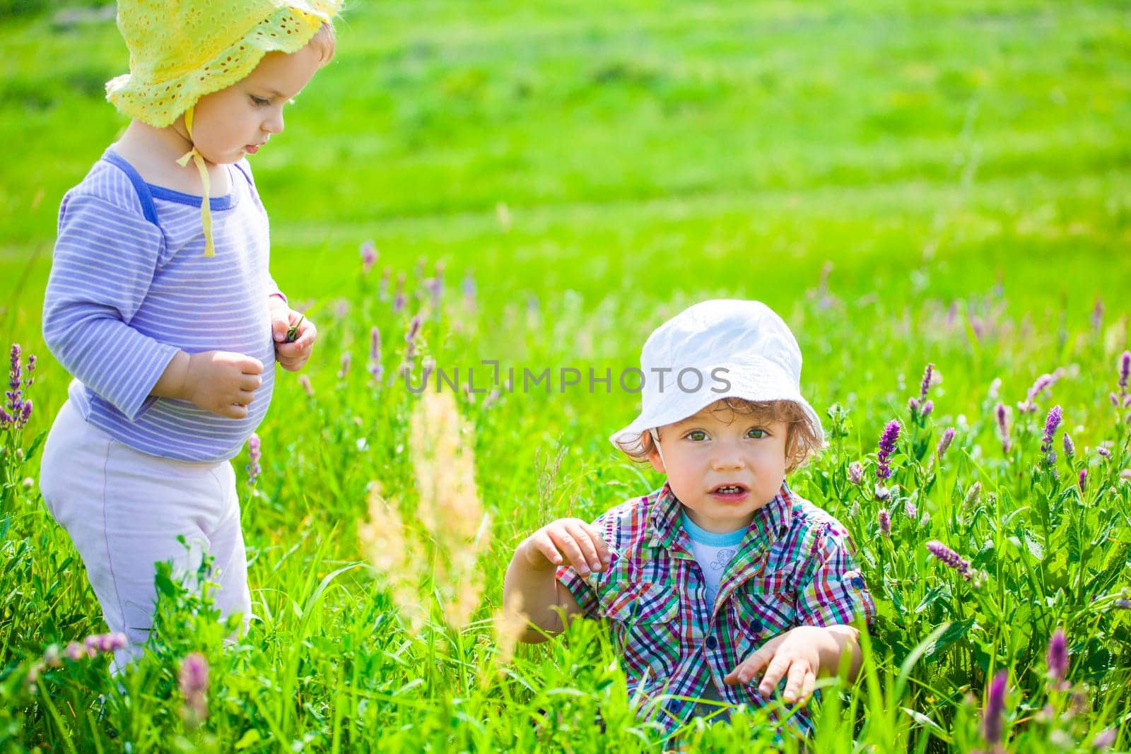 Portrait of 1 year old baby boy and baby girl outdoor on a meadow.