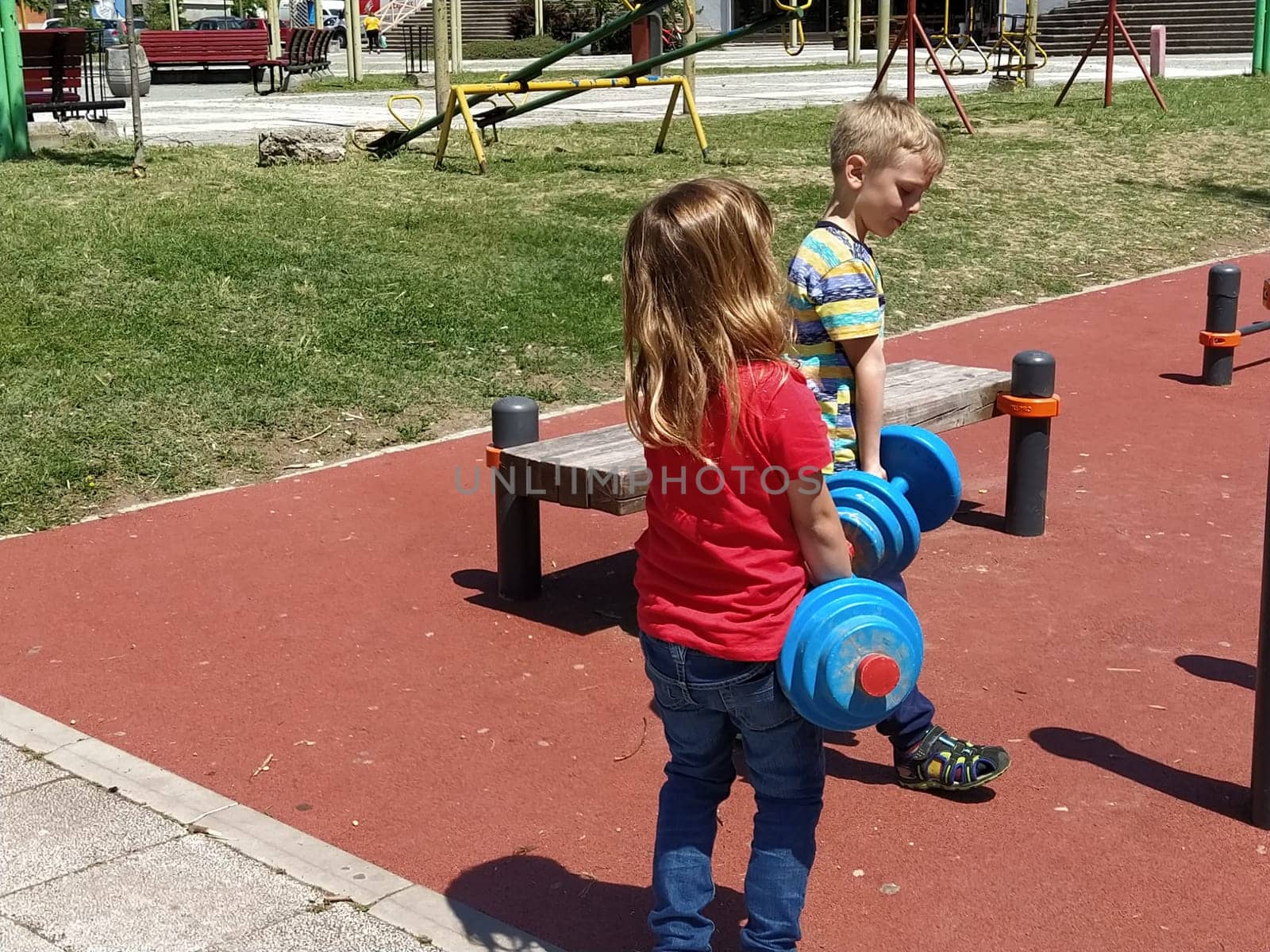 June 6, 2020, Sremska Mitrovica, Serbia. Children go in for sports on the playground. Exercises with kettlebells. Lifting weights. Physical education and sports. Children's fun in the summer.