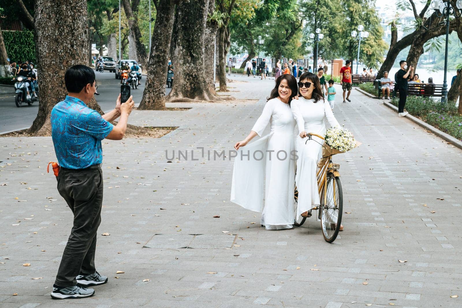 Hanoi, Vietnam, November 15, 2022: Women are posing for a photo in the Hoan Kiem Lake park in Hanoi