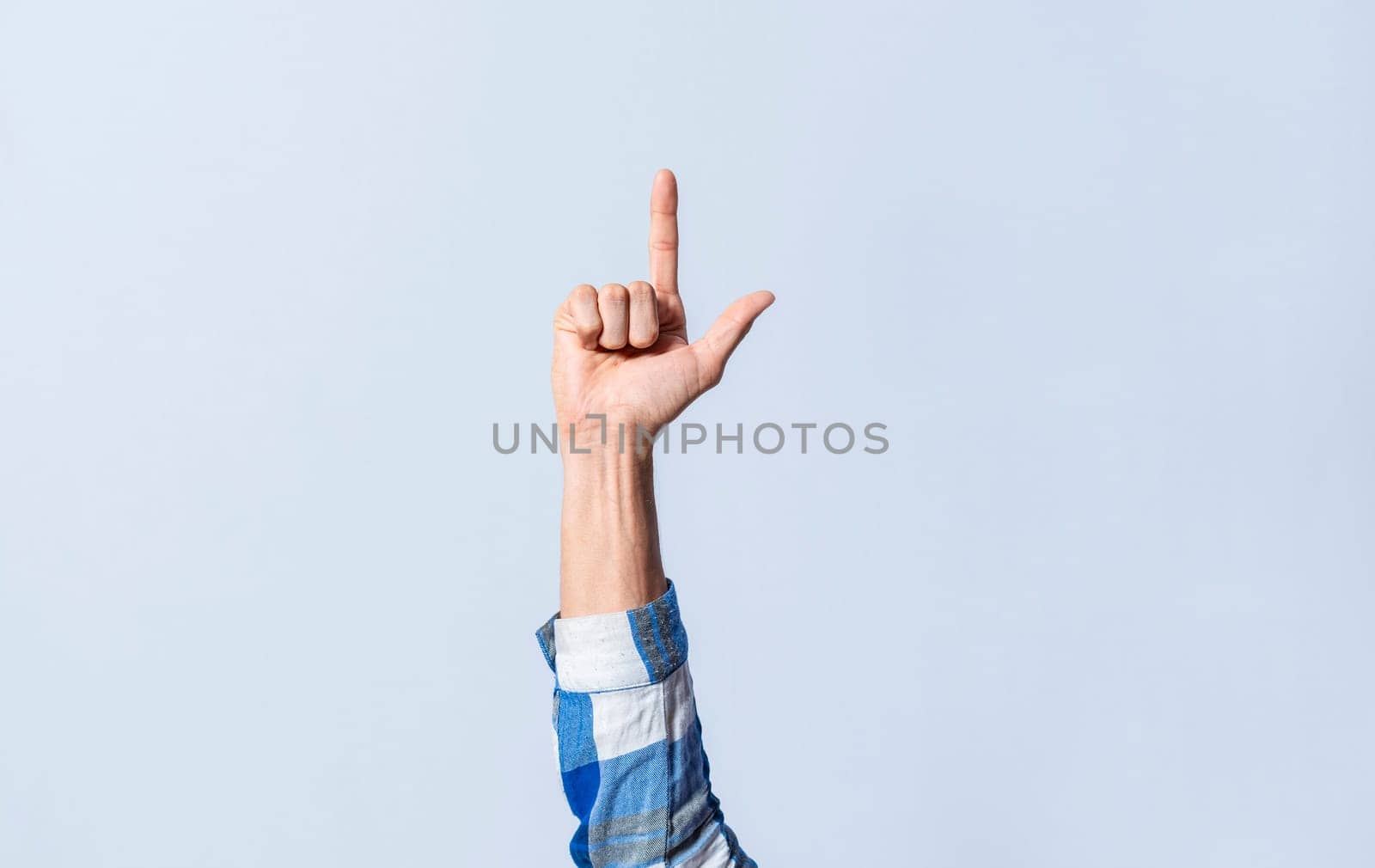 Hand gesturing the letter L in sign language on an isolated background. Man's hand gesturing the letter L of the alphabet isolated. Letters of the alphabet in sign language