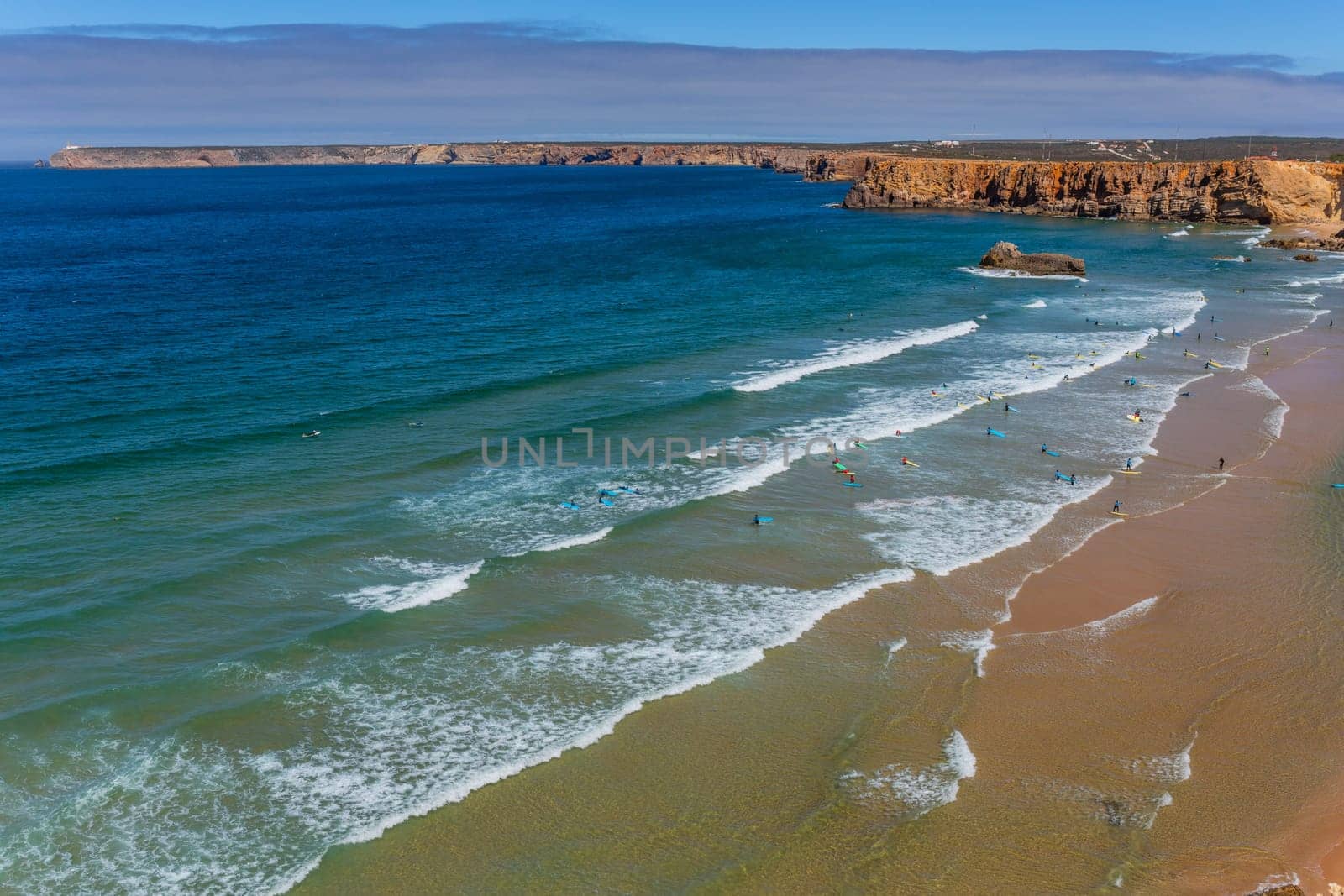 Sagres, Portugal - August 25, 2022: View of surfers on sandy beach near Sagres village in Algarve, Portugal
