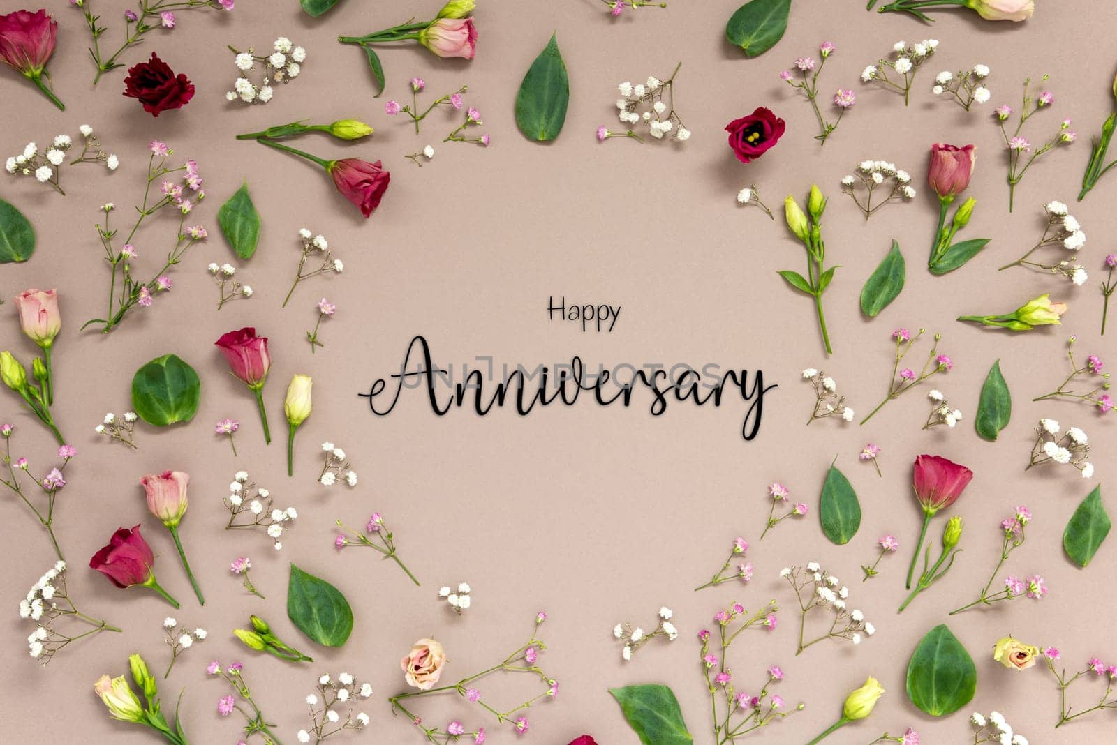 Flower Arrangement With English Text Happy Anniversary. Colorful Spring Blossoms And Flowers Like Roses Building A Frame. Flat Lay With Brown Paper Background