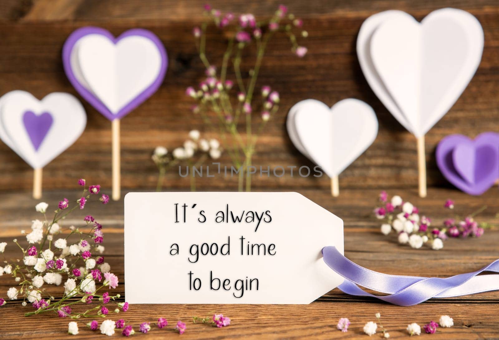 Label With English Quote It Is Always A Good Time To Begin. Purple And Lilac Decoration And Spring Flower Arrangement. Heart Symbols With Wooden Background.