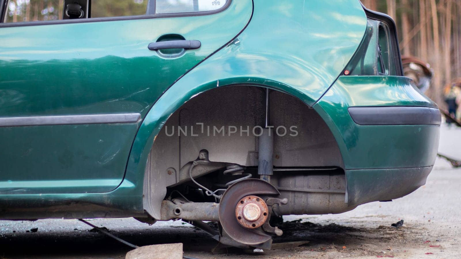 A car without a rear wheel on the side of the road. The rear hub of a car without a wheel. An old car without wheels in a parking lot with stolen wheels and headlights. Car on bricks