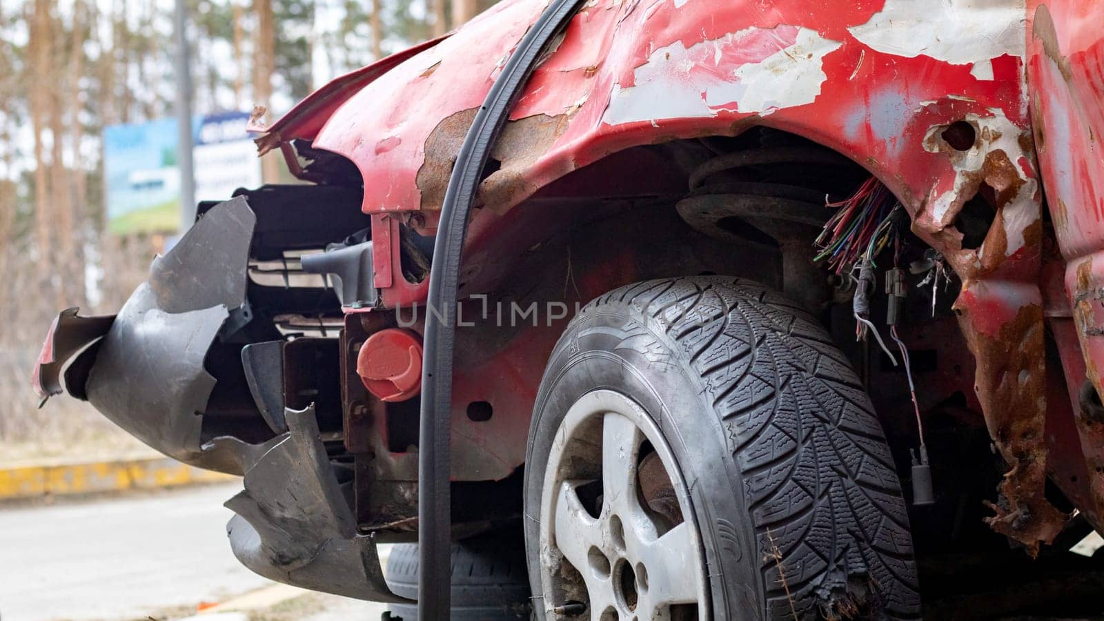 Broken rumpled red car after a severe accident with a skewed body, after a powerful blow. Accident on the street, damaged car after a collision in the city. Auto accident. Broken car on the street