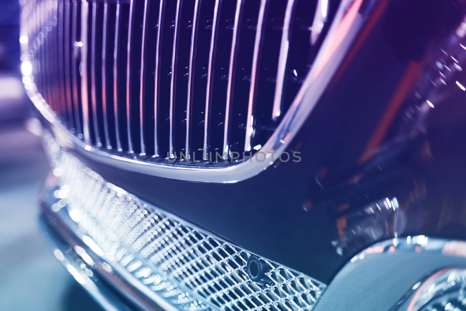 closeup of black classic car with chrome front radiator grill intake cooling air system