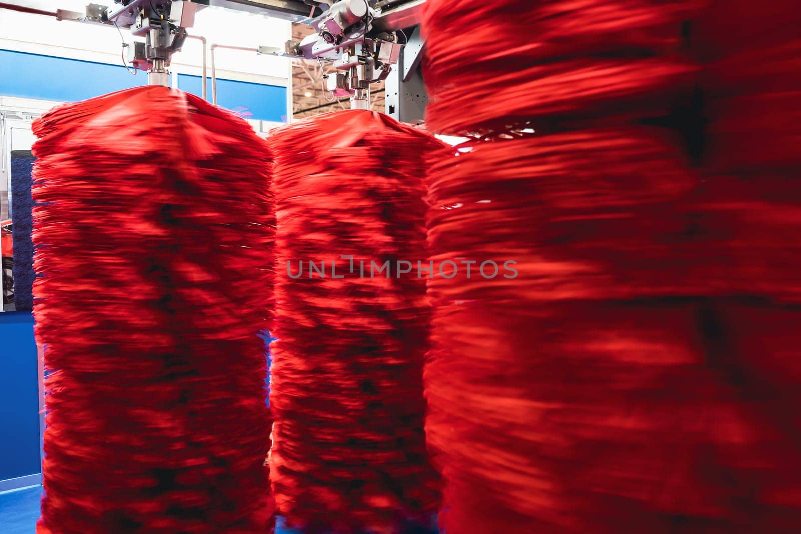 detail of an automatic car wash system in cleaning station with large red textile cleaning brushes rotating with motion blur
