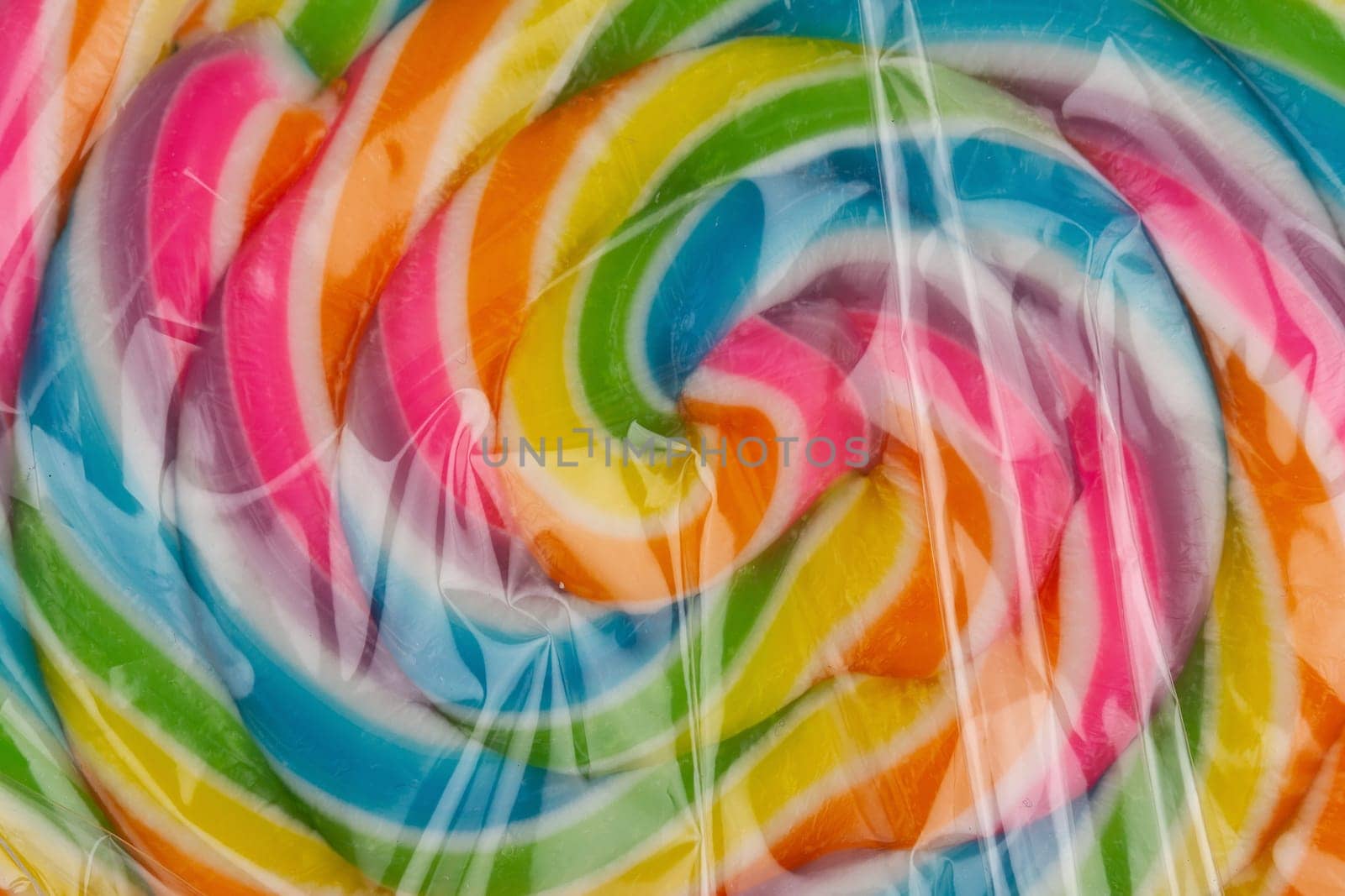 closeup detail of colorful lollipop candy on a stick in transparent plastic packaging isolated on white background