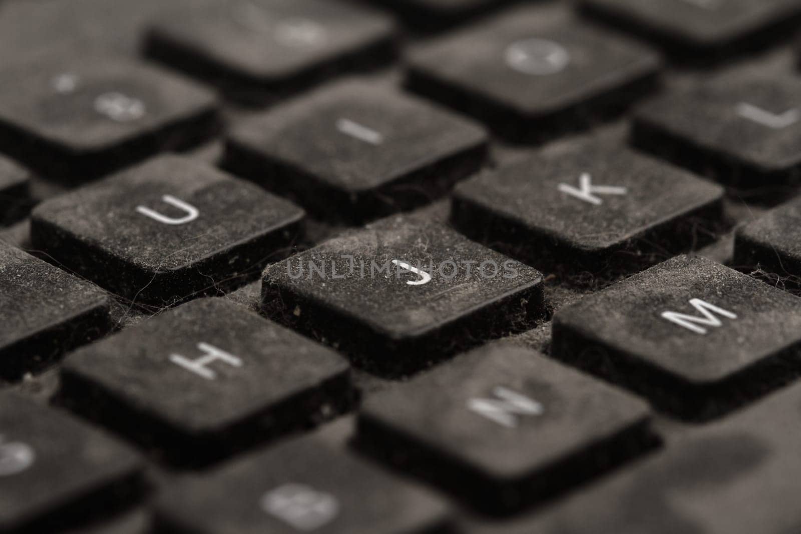 front view closeup of old black keyboard with keys covered in dust and dirt isolated on white background
