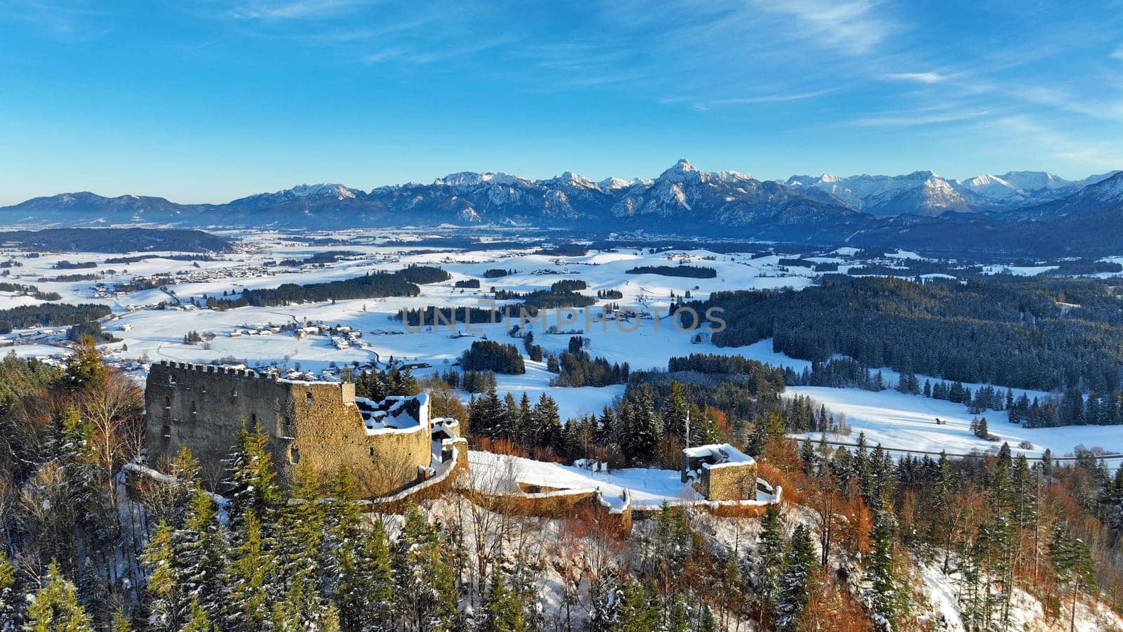 Drohnenaufnahme von der Ruine Burg Eisenberg vor den Allgäuer Alpen im Winter
