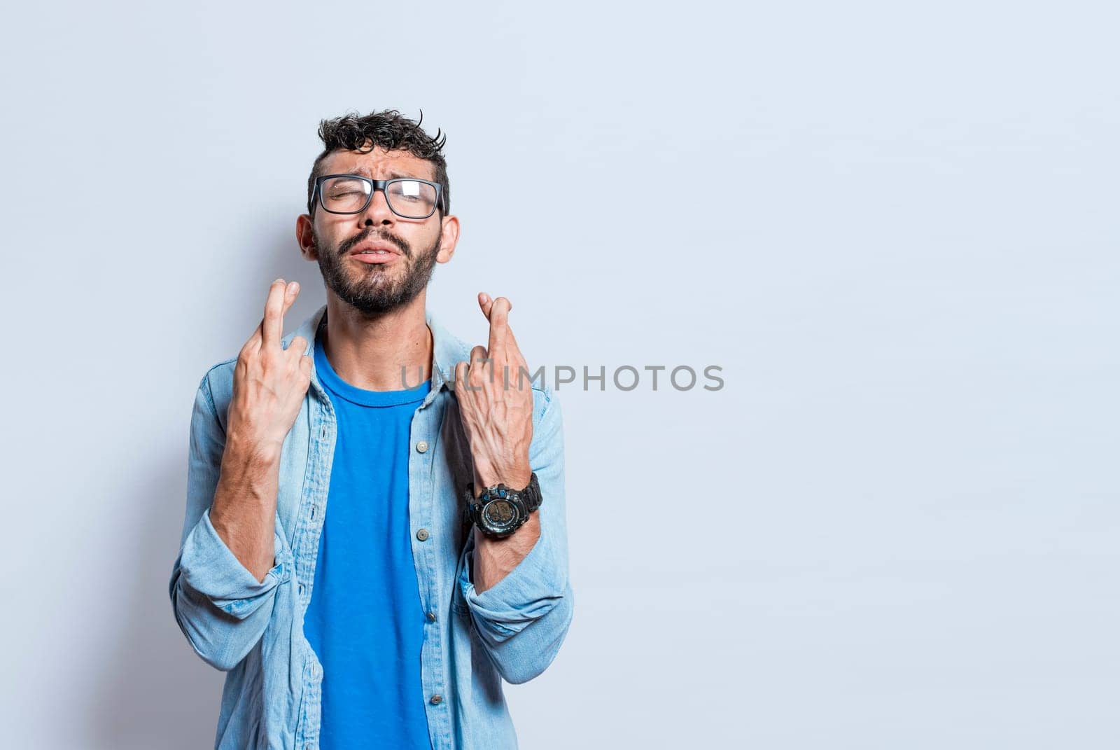 Worried person crossing his fingers making a wish, concerned man apologizing, hopeful man asking for help or apologizing, superstitious man crossing his fingers asking for something