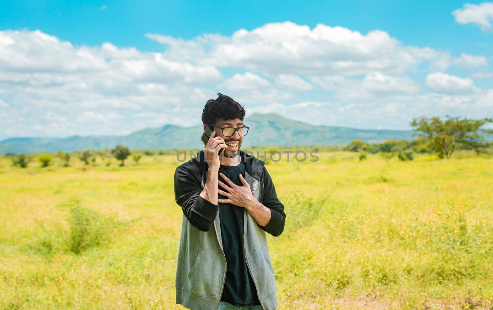 Smiling man calling on the phone on the field, people talking on the cell phone in the field. Man calling on the phone in the field, A man in a beautiful field talking on the phone