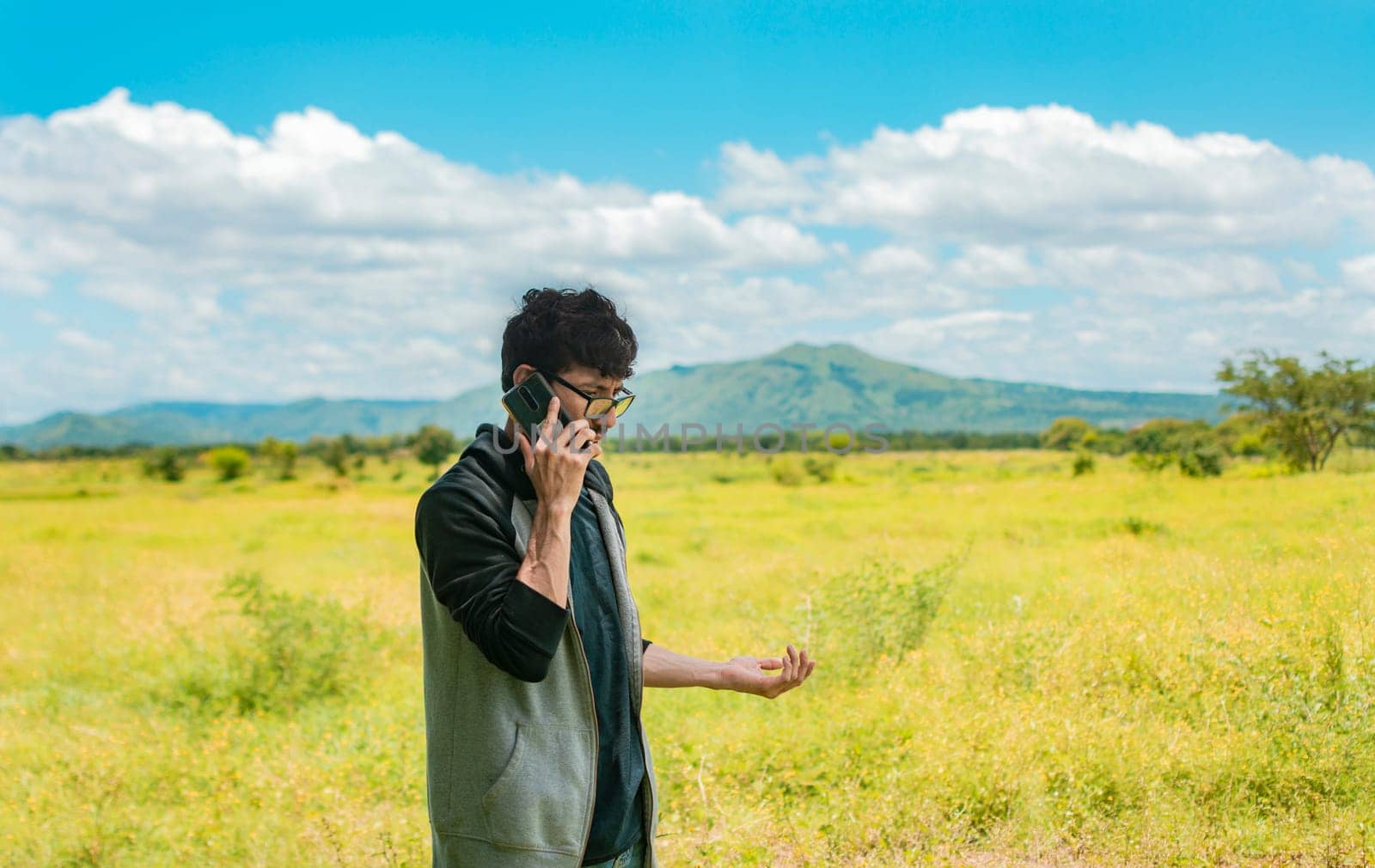 Man calling on the phone in the field, A man in a beautiful field talking on the phone, person with cell phone calling on the phone in the field, people talking on the cell phone in the field