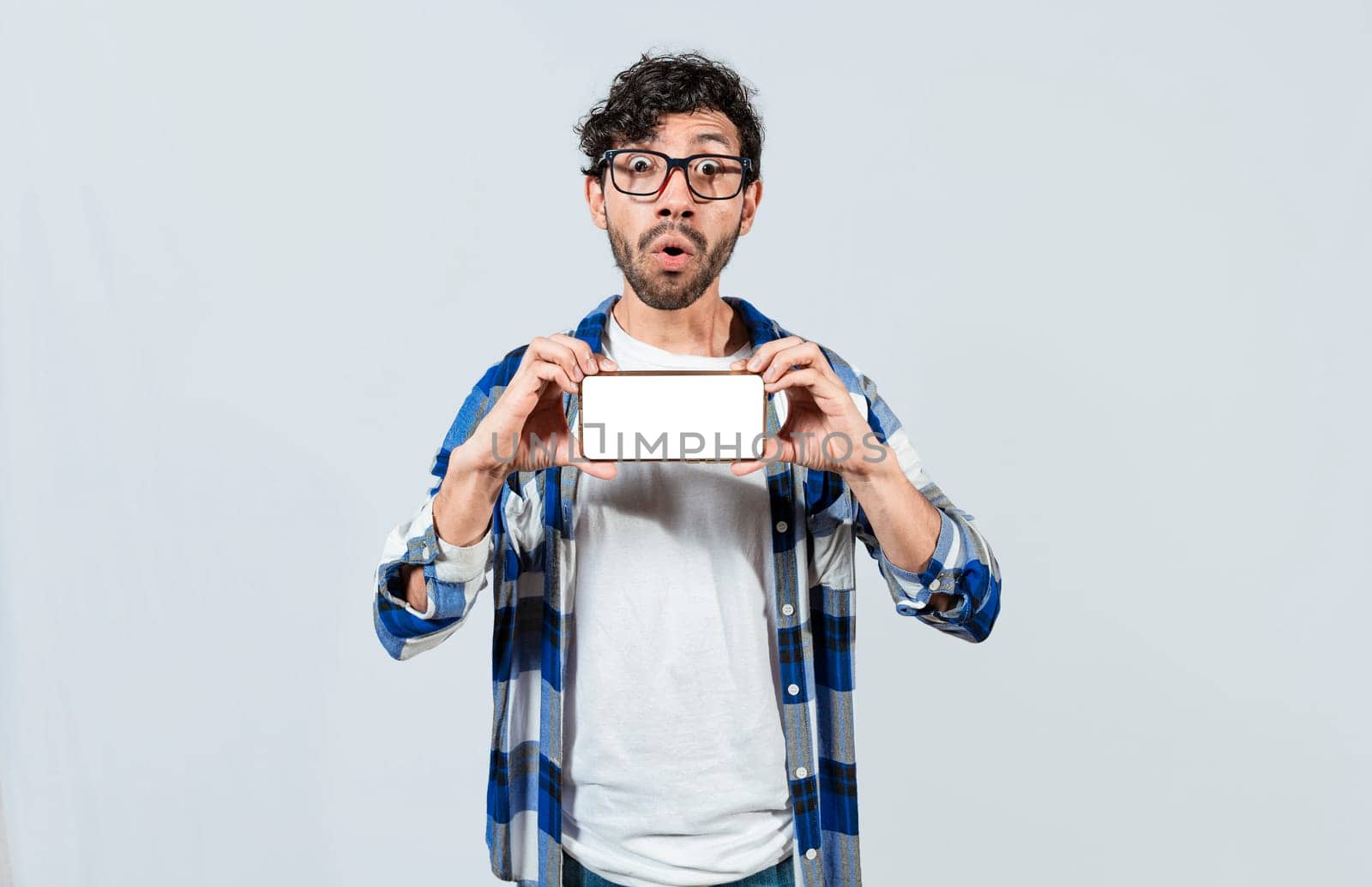 Surprised guy in glasses showing blank screen of smart phone. Amazed young man showing ad on cellphone. Surprised handsome man showing the horizontal screen of his cell phone