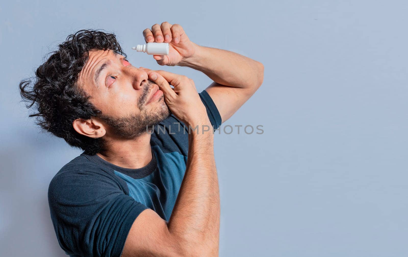 Person applying dropper to irritated eye. People applying refreshing drops to irritated eye. Man putting a dropper in his eye isolated. Man with irritated eye applying drops with a dropper