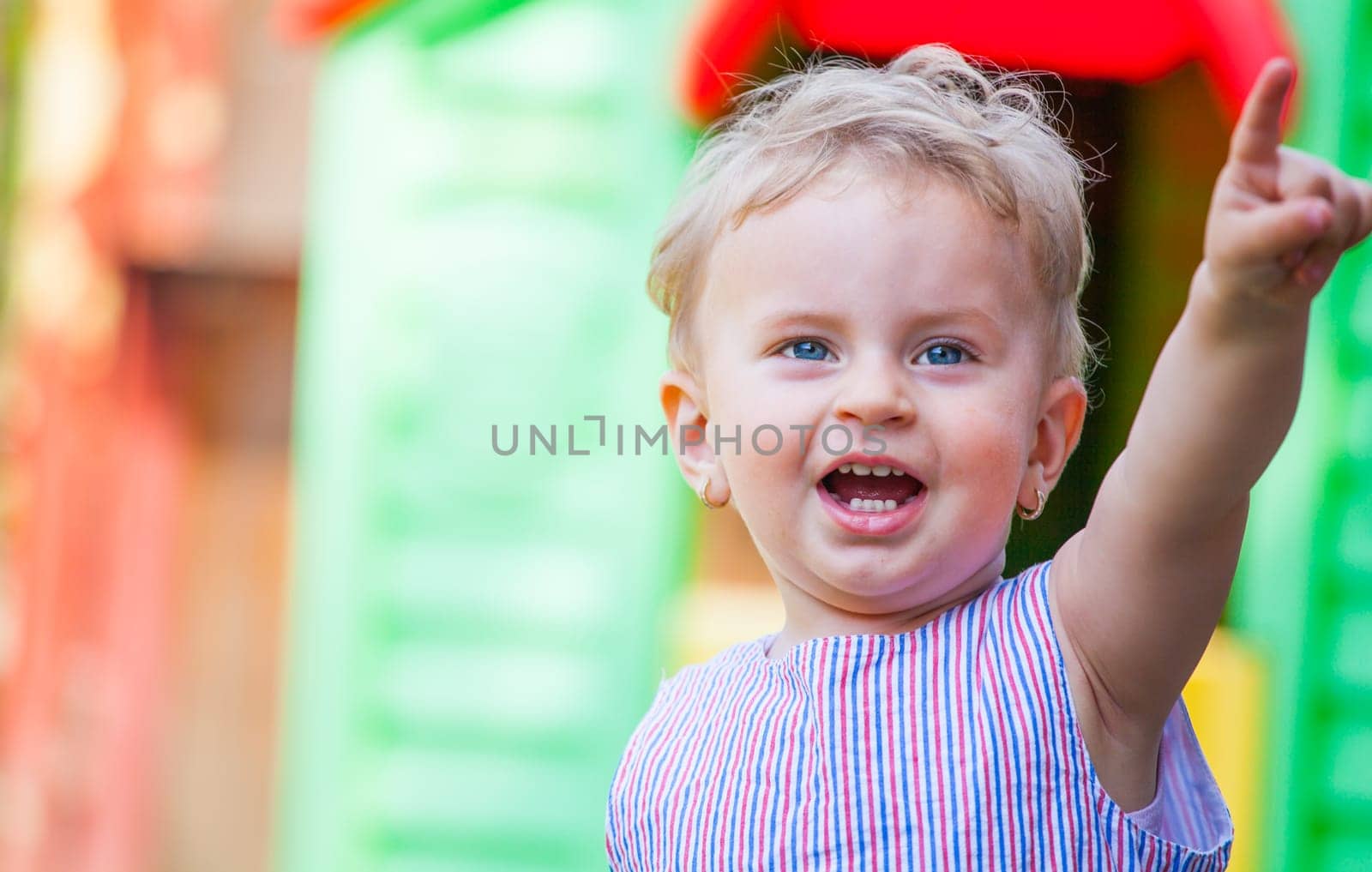 Portrait of 1 year old baby girl pointing her finger, at home in the garden.
