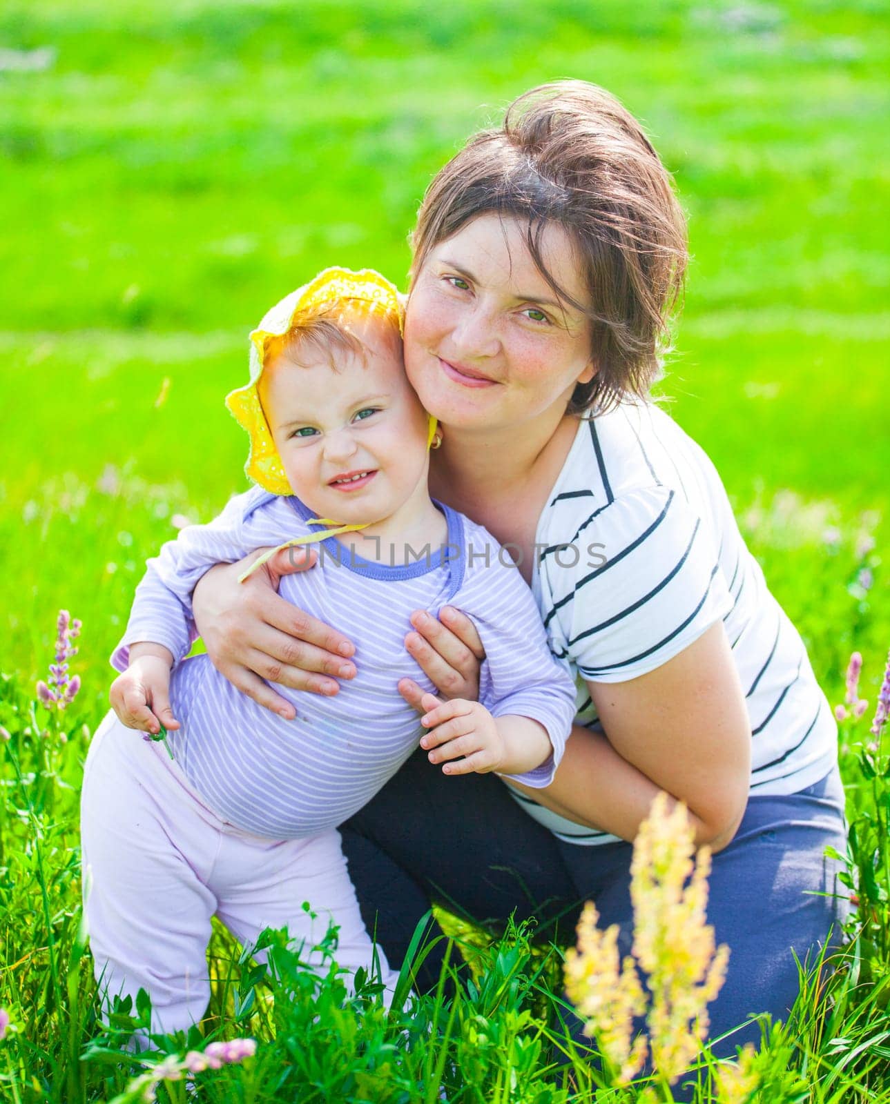 Portrait of 1 year old baby girl with her mother on a meadow.