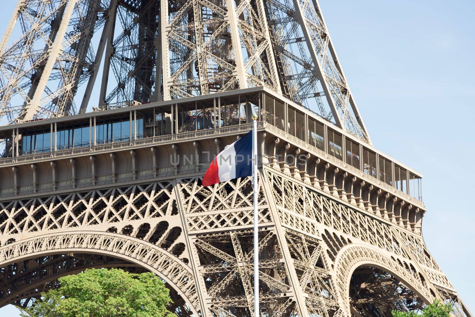 The Eiffel Tower in Paris, France with the french flag in front of it.