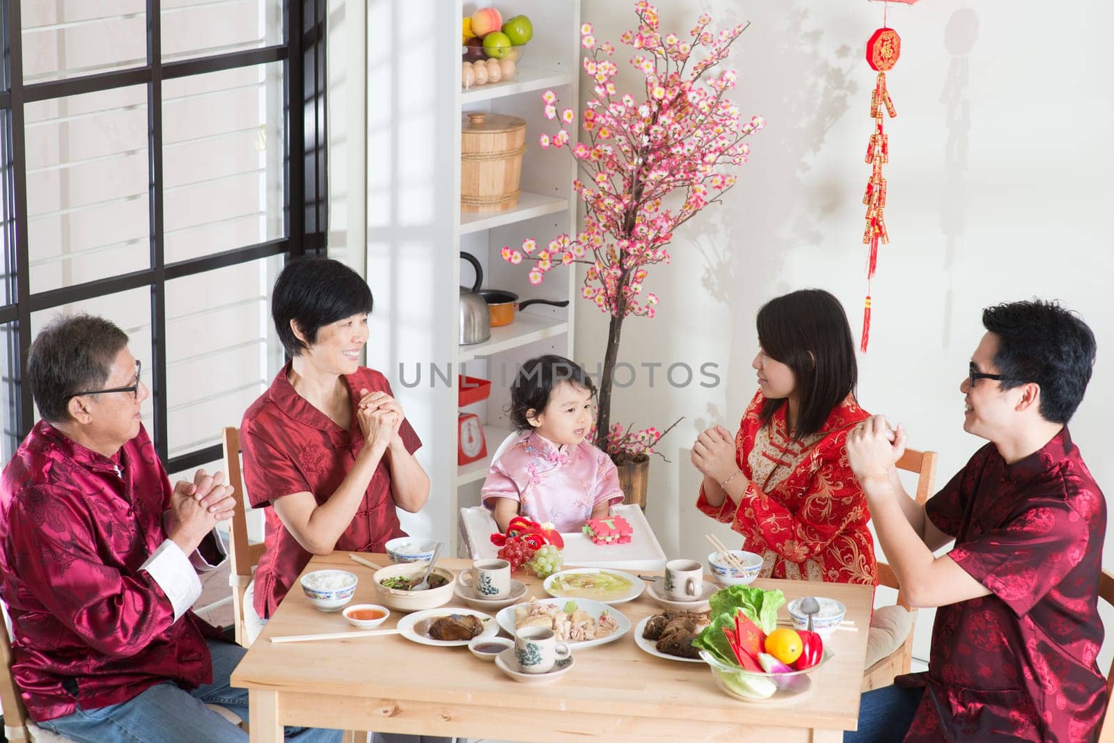 Chinese New Year festival, reunion dinner. Happy Asian Chinese multi generation family with red cheongsam dining at home.
