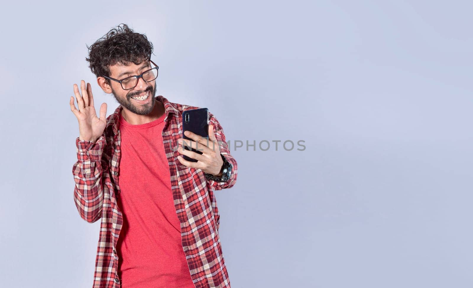 Smiling man making video call with his cellphone isolated, Positive teen guy making video call waving hands, Concept of smiling man saying hello by video call on cellphone