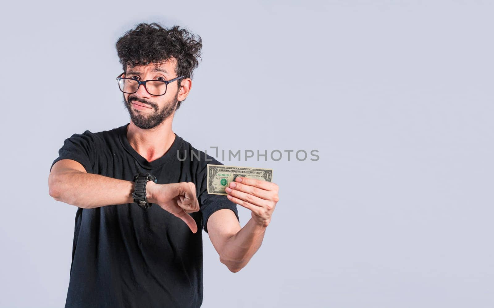 Sad person holding a banknote with his thumb down, Sad man with a dollar bill, Concept of man with money problems