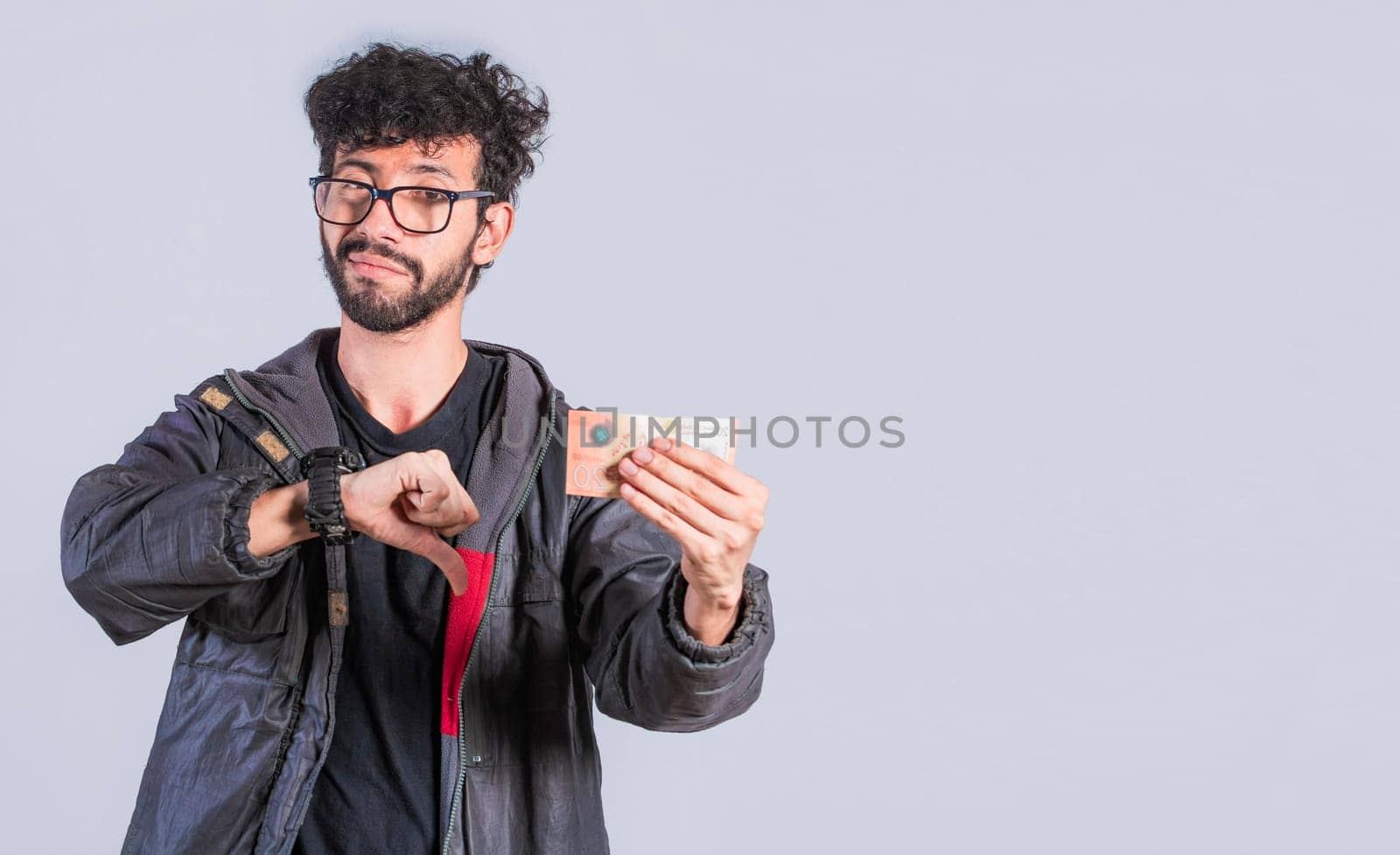 Unhappy person with a Nicaraguan banknote with his thumb down, Concept of a person with money problems. Sad person with a bank note with his thumb down