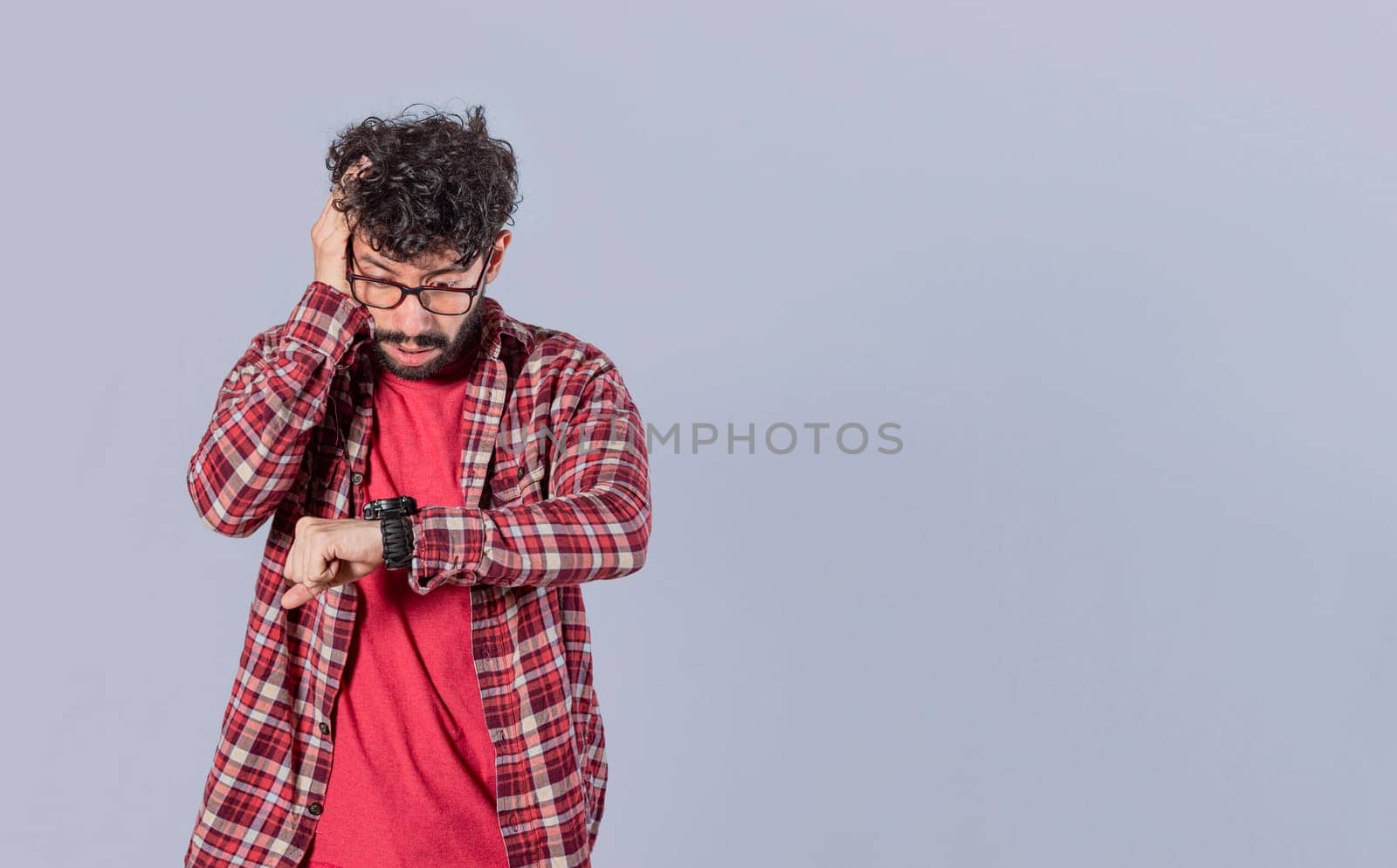 Worried young man looking at the time on the clock, worried man looking at his watch, scared man looking at his watch, isolated