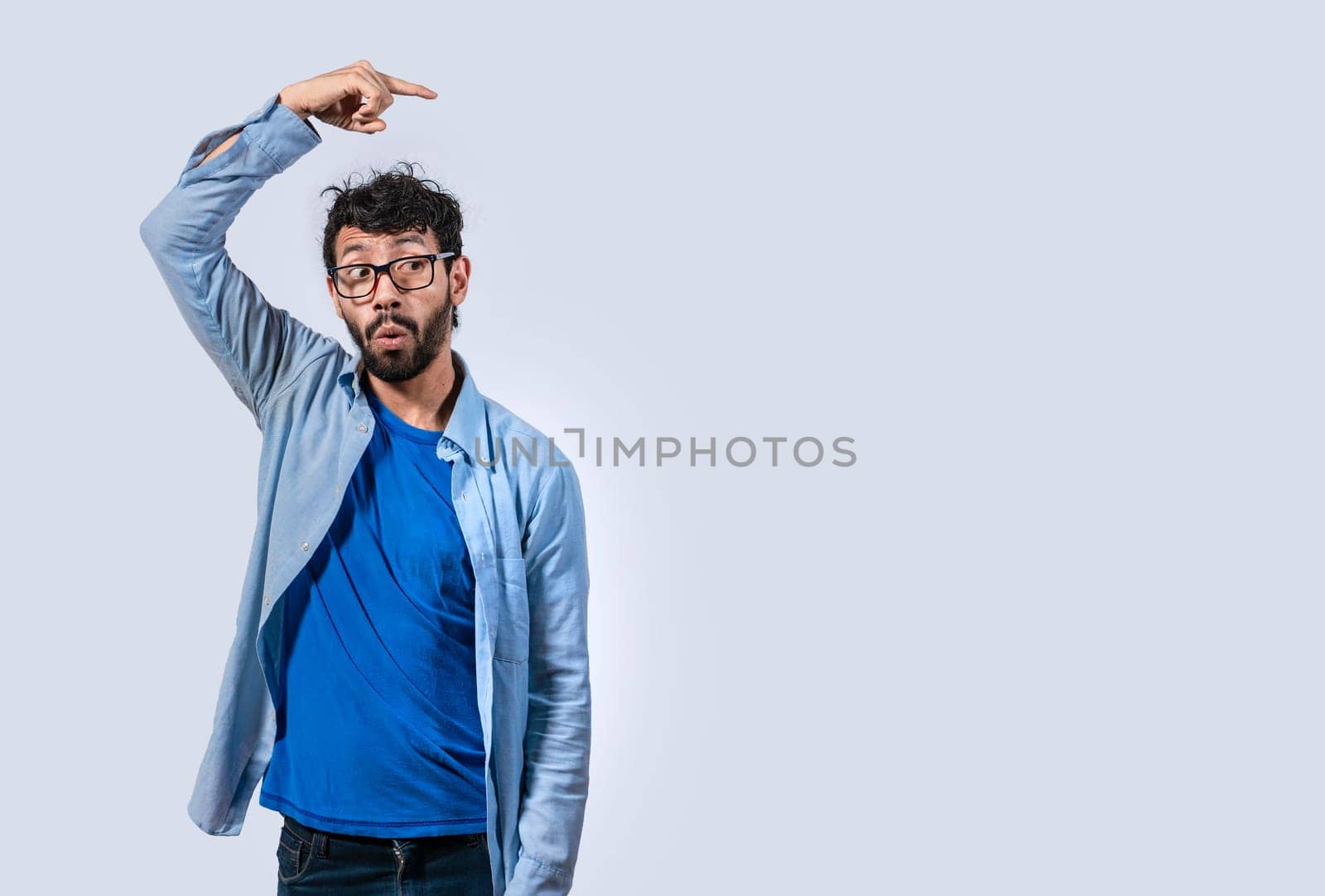 Surprised handsome man pointing to the side, Concept of latin man pointing a banner to the side, Surprised guy pointing a poster