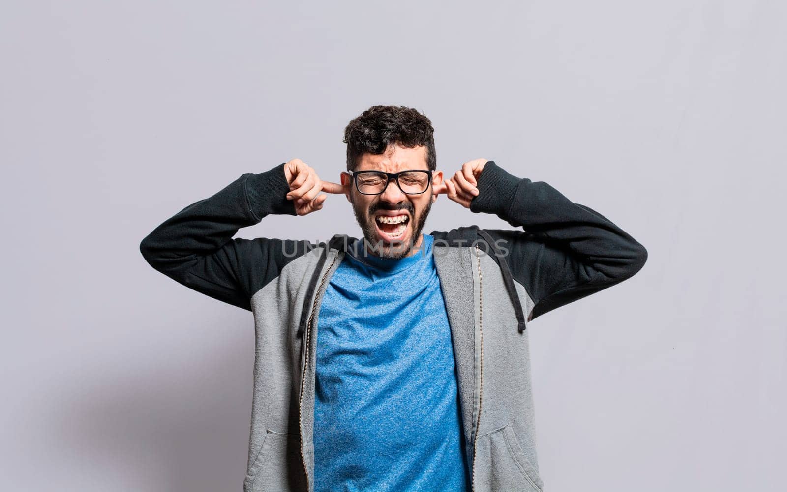 Irritated person screaming covering his ears, desperate person avoiding hearing bad news, stressed man screaming covering his ears