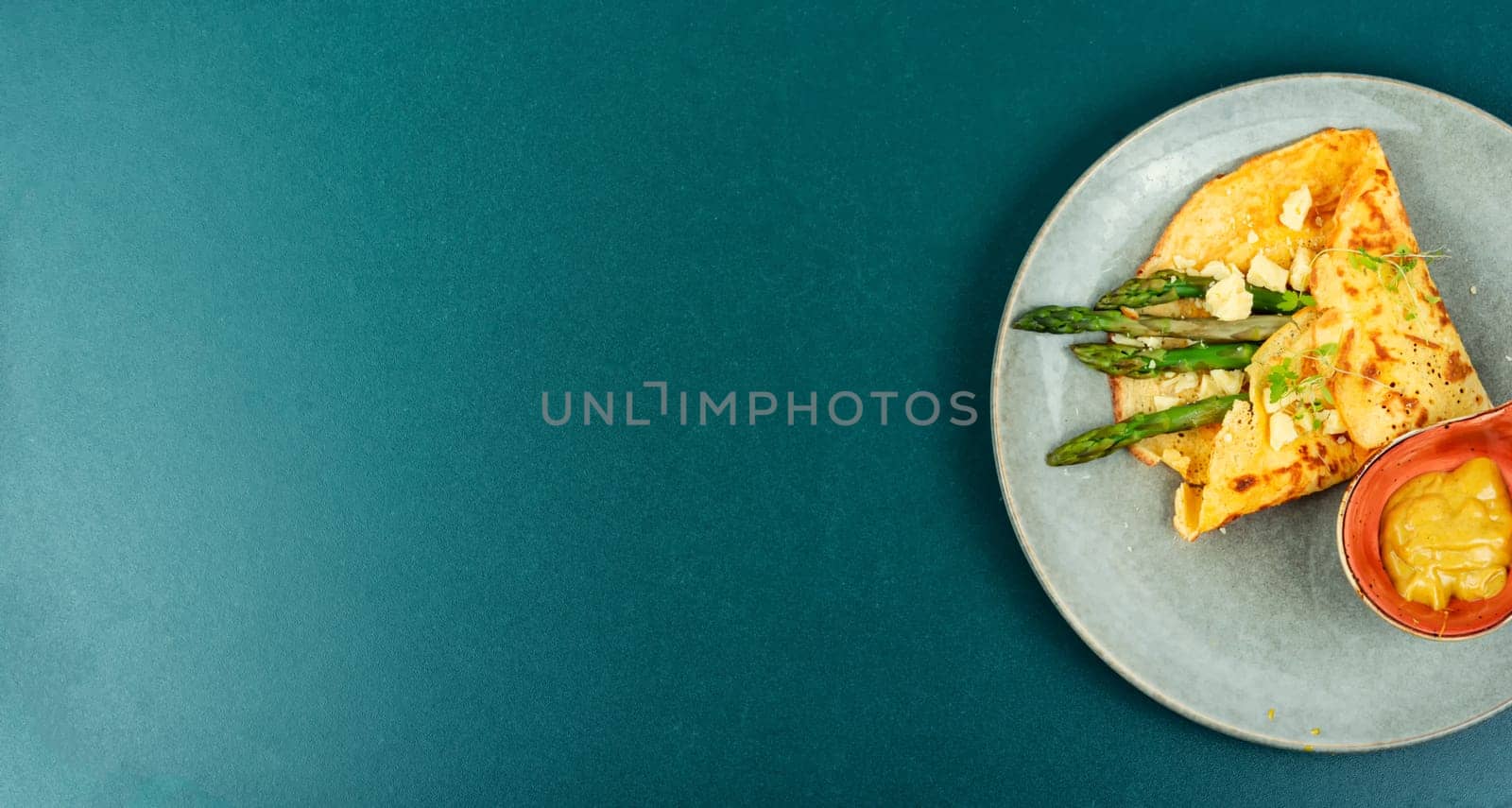 Tasty omelet or vegan crepes stuffed with green asparagus,cheese and herbs. Healthy breakfast.