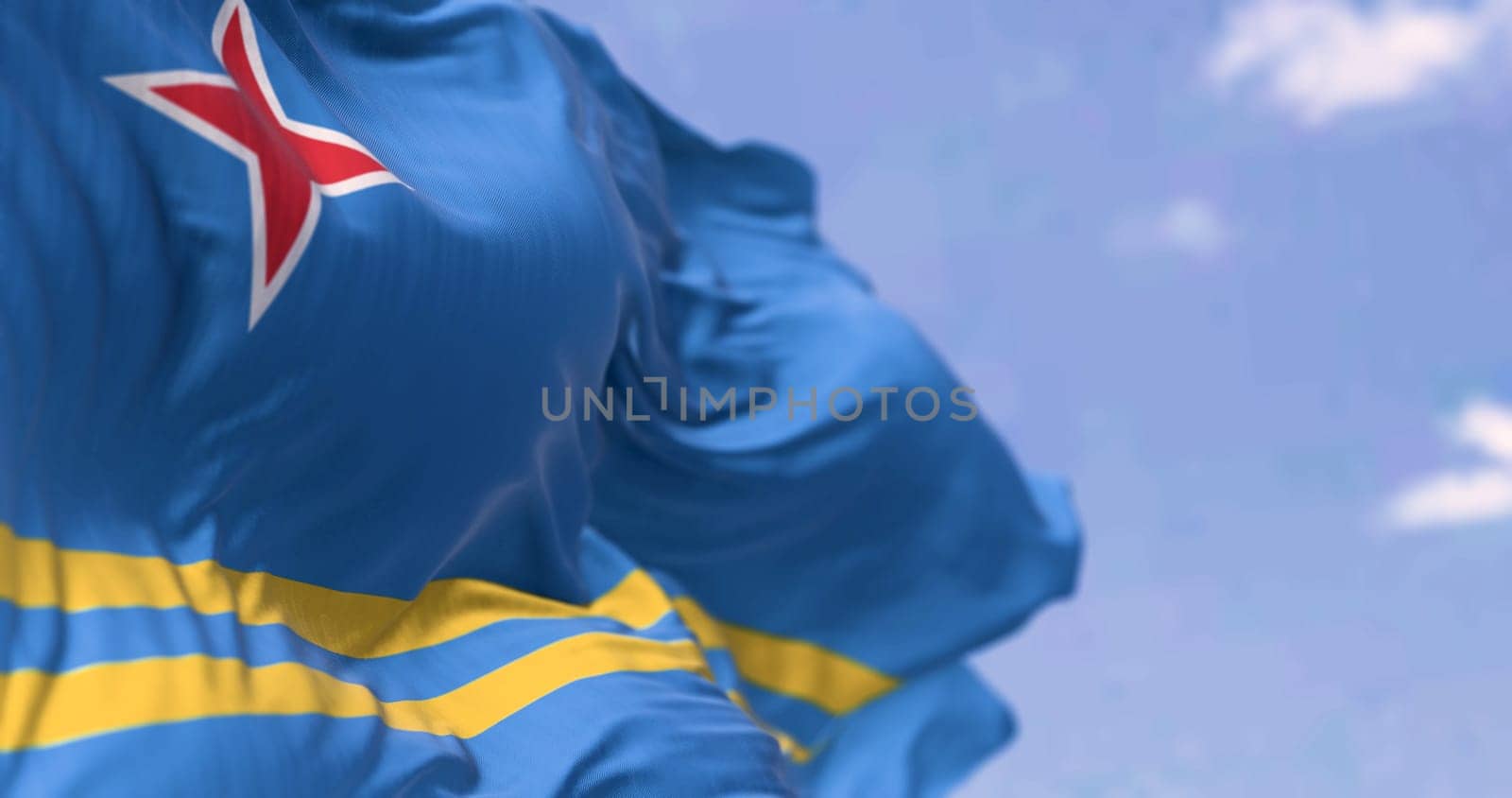 Flag of Aruba waving in the wind on a clear day. Light blue field, 2 yellow stripes, 4-pointed red star. Colors represent sea, abundance, peace, and origins. 3d illustration render. Selective focus