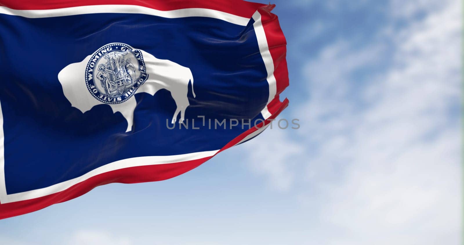 Wyoming state flag waving on a clear day. Bison silhouette. Red for Native Americans and pioneers. White for purity. Blue for sky, fidelity, justice. 3d illustration render. Fluttering fabric.