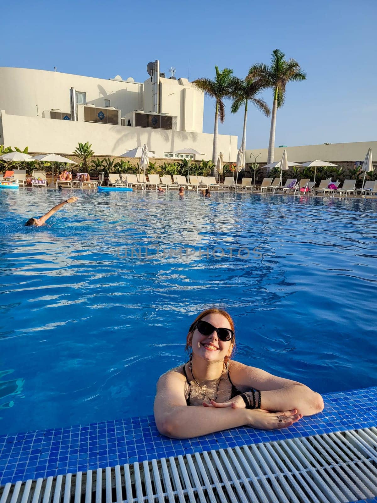 Young girl in sunglasses in the water of a swimming pool