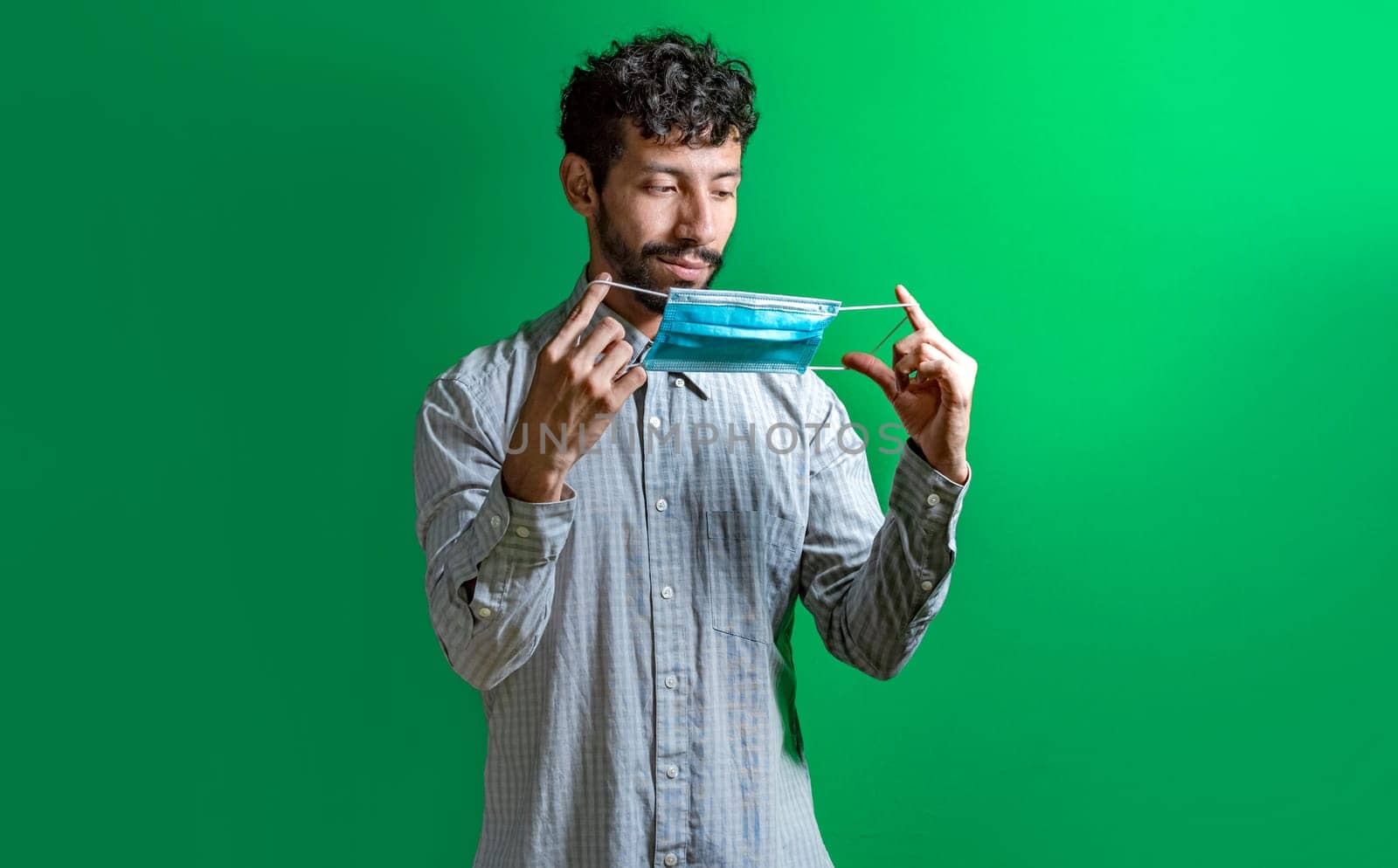 Young man putting on the mask on isolated background, concept of the correct use of the mask