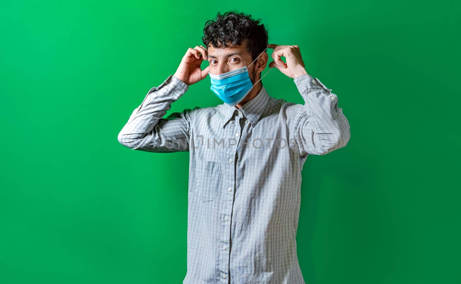 A man putting on the mask on isolated background, Handsome man putting on a surgical mask isolated. Concept of a person correctly putting on a surgical mask isolated