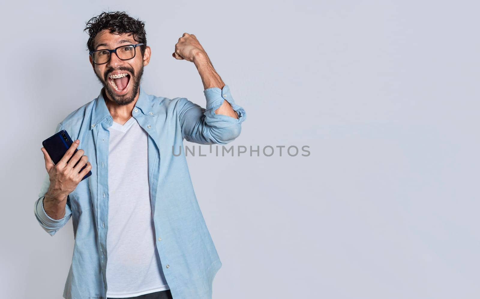 Excited man winning a prize from his cellphone. Excited handsome man looking at smartphone celebrating something. Happy person holding a smartphone and celebrating