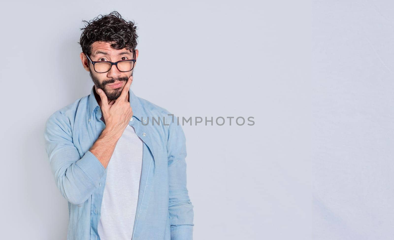 Handsome man rubbing his beard with a doubtful expression, Person rubbing his chin with a doubtful expression. handsome bearded man with doubt expression isolated