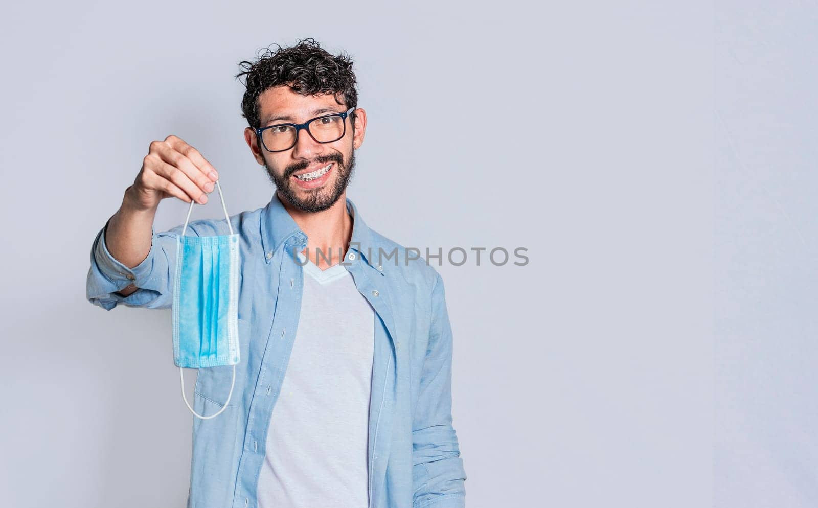 Smiling man offering you a surgical mask on isolated background, Person offering you a medical mask isolated