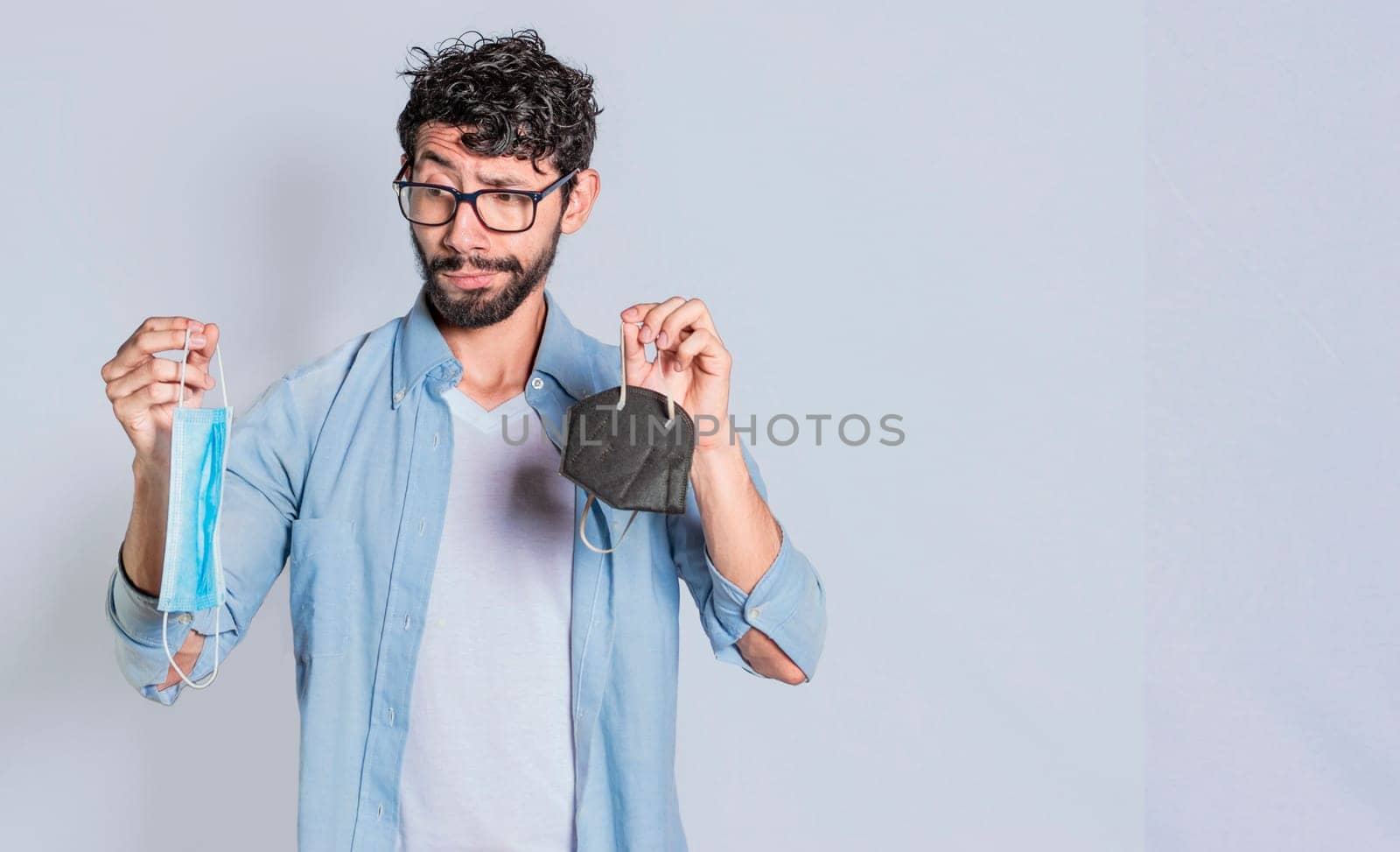 Handsome man deciding which surgical mask to wear, Person deciding to wear a surgical mask isolated, Concept of people deciding which mask to wear