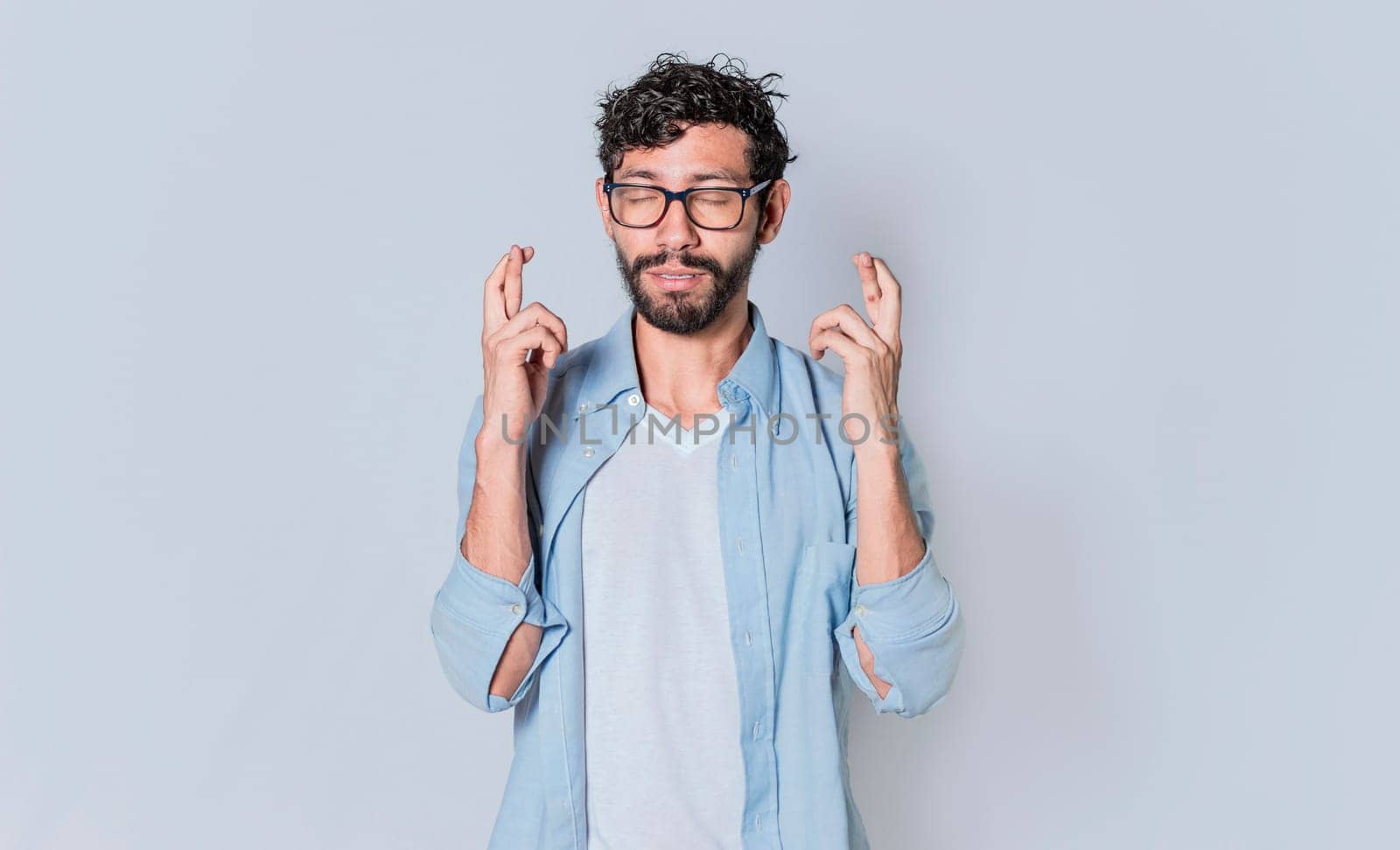 Happy man making a wish, latin guy crossing his fingers making a wish