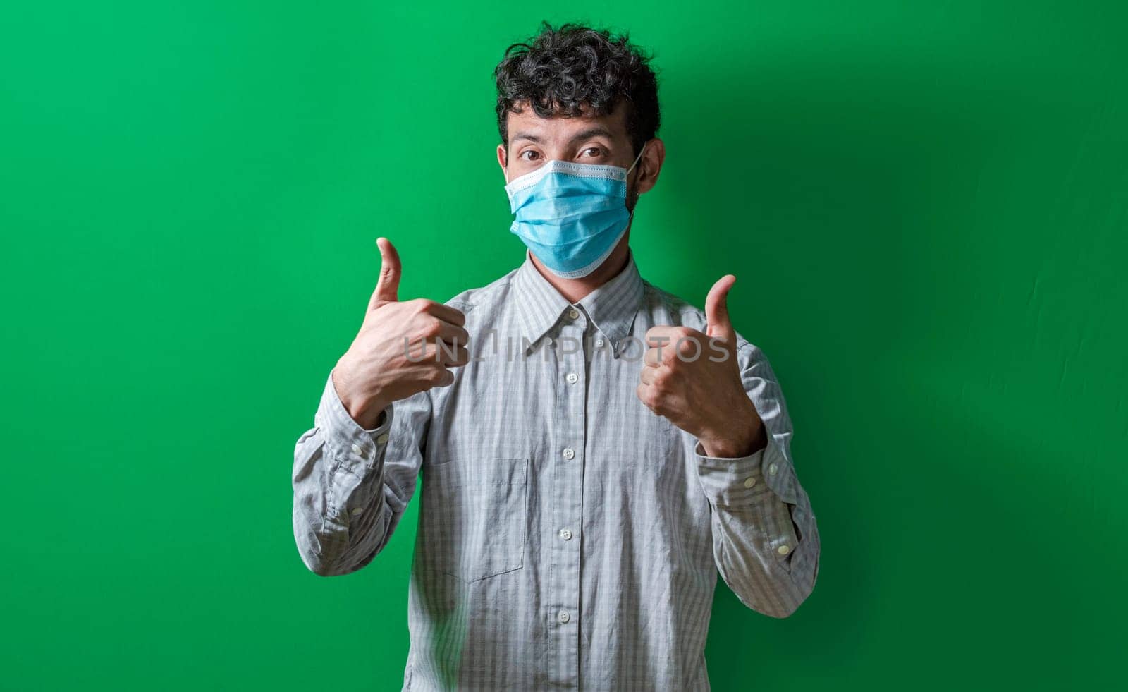 Isolated man with mask on giving thumbs up, Person giving thumbs up with mask on isolated. Concept of the correct use of the surgical mask.