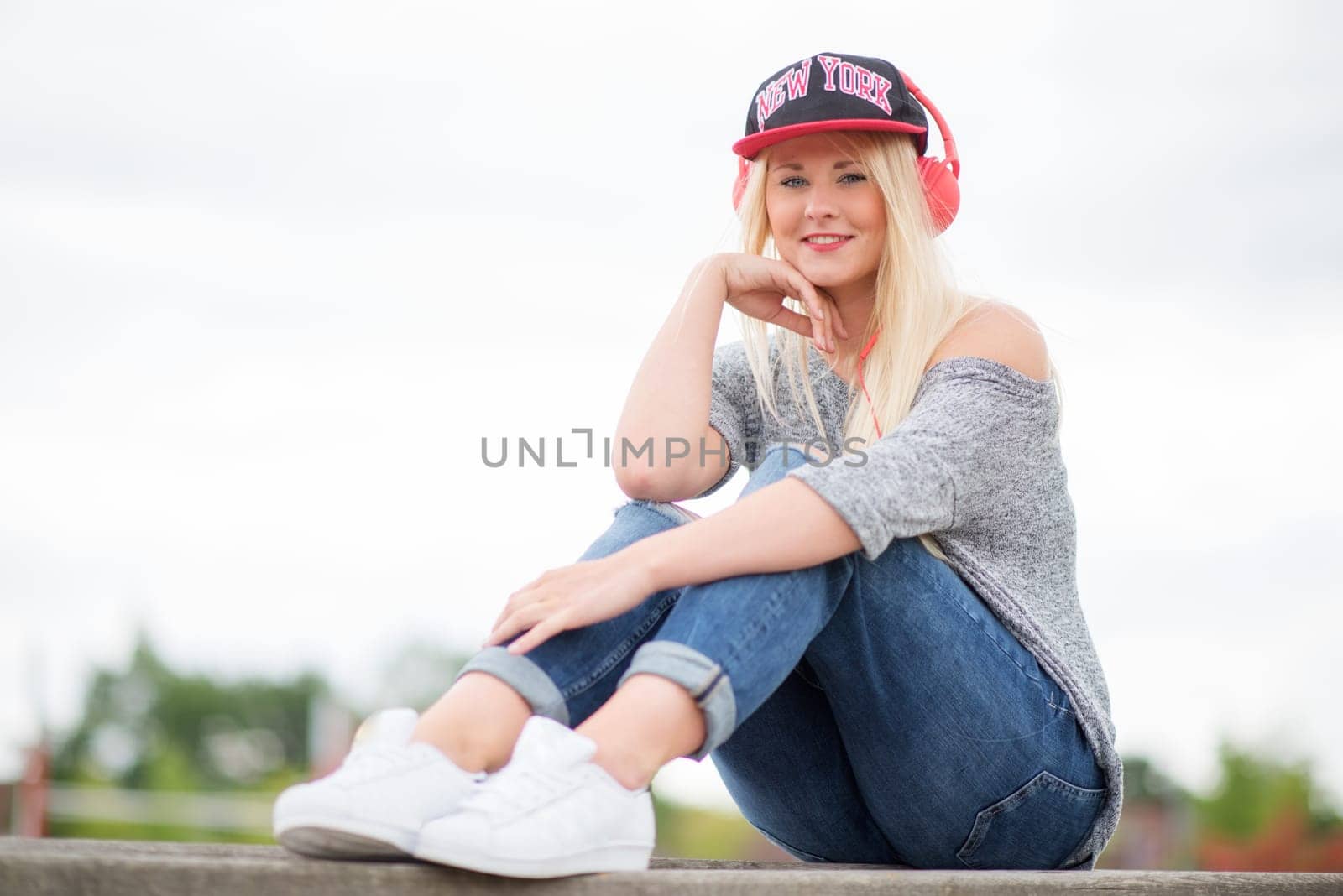 Girl with headphones and basecap listens to music outside