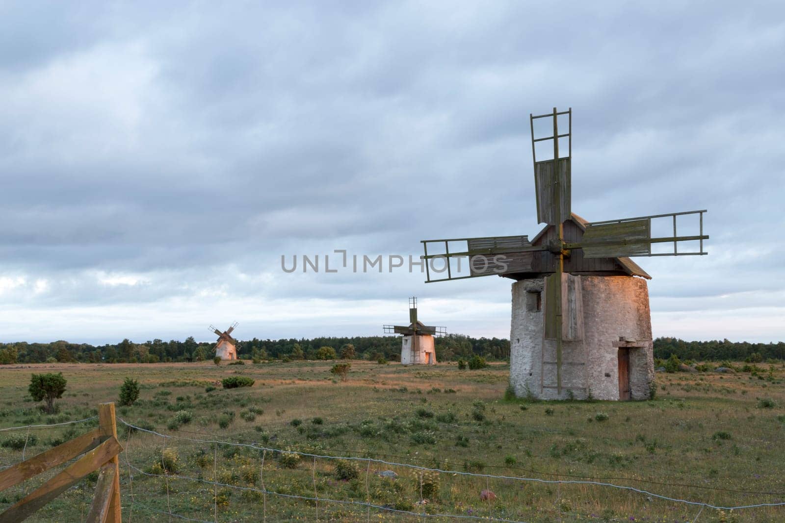 Windmills in Field in Gotland, Sweden with clouds behind them.