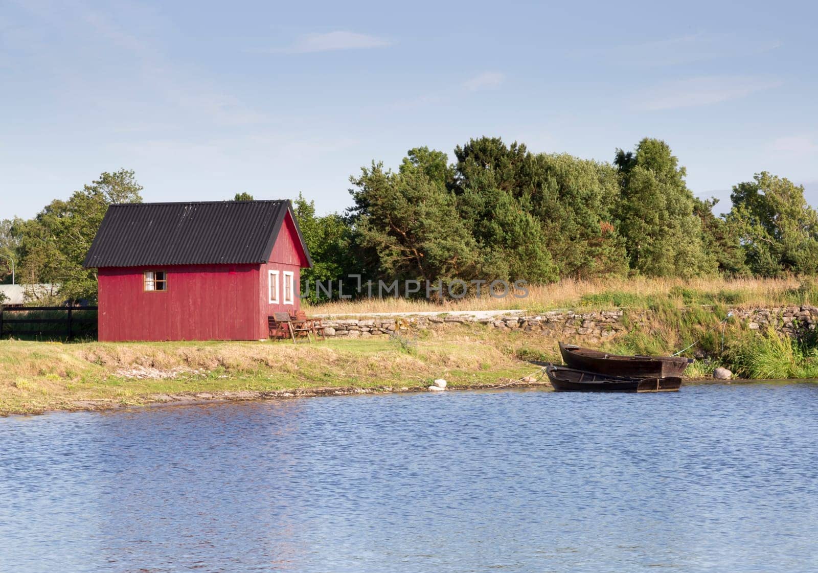 Red House by Rowing Boats and water with blue sky.