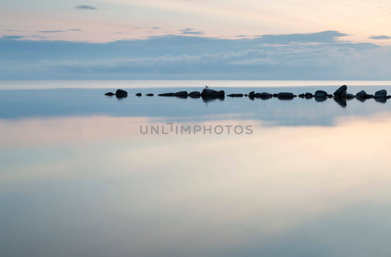 Breakwater Rocks in Calm Sea with clouds and reflextions in the water.